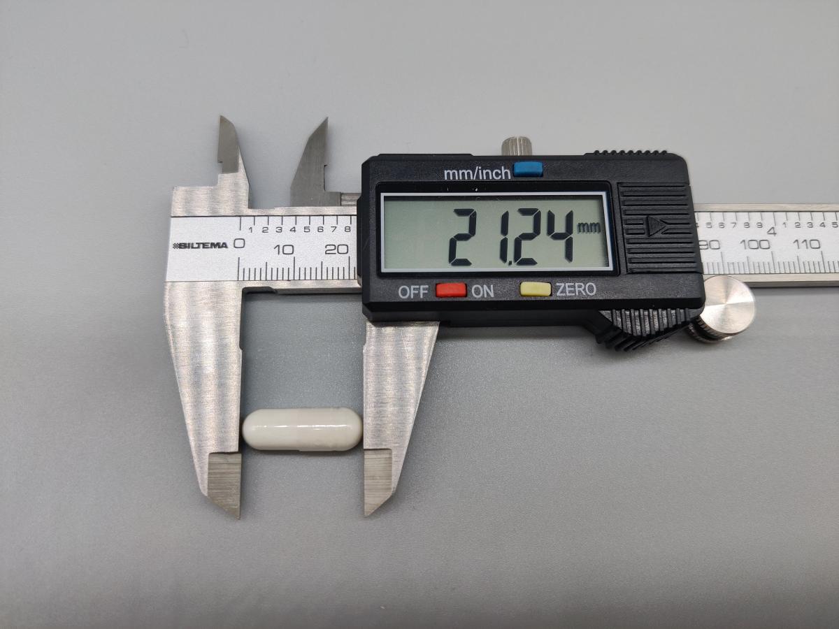 Skjutmått som visar kapselns längd runt 21 mm, dokumenterat av oss