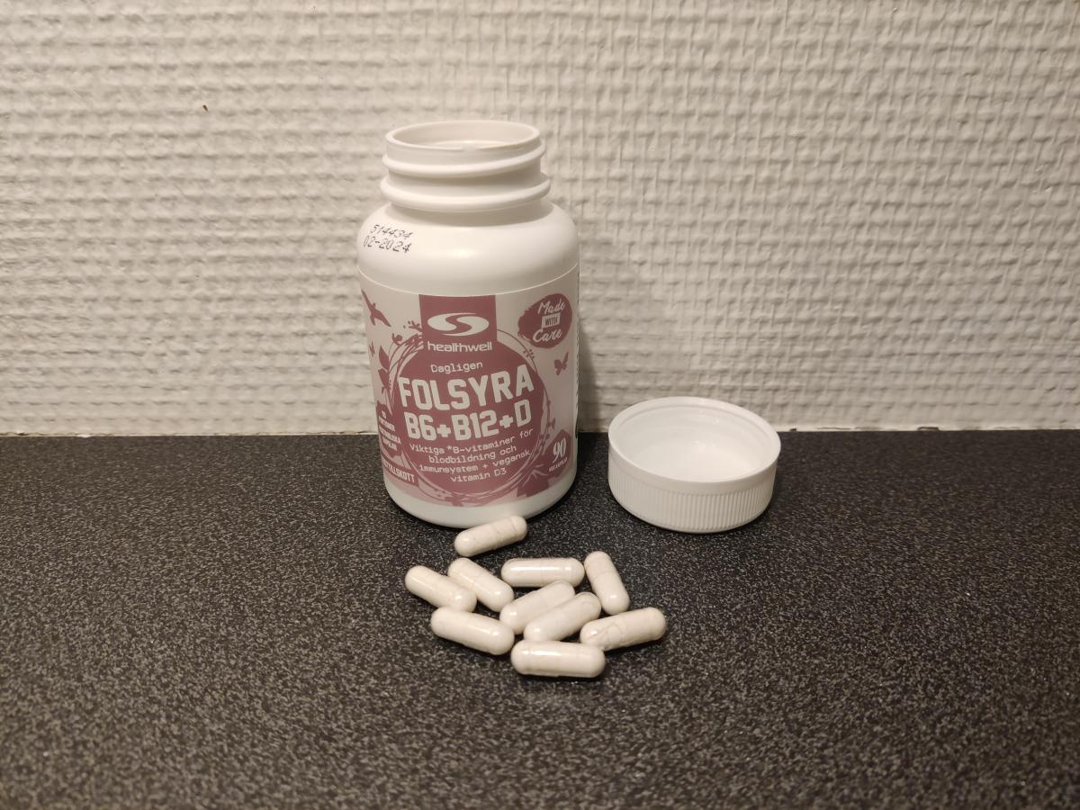 Healthwell Folsyra B6 B12 D med öppet lock och kapslar på bänkskiva, foto taget av oss under testet