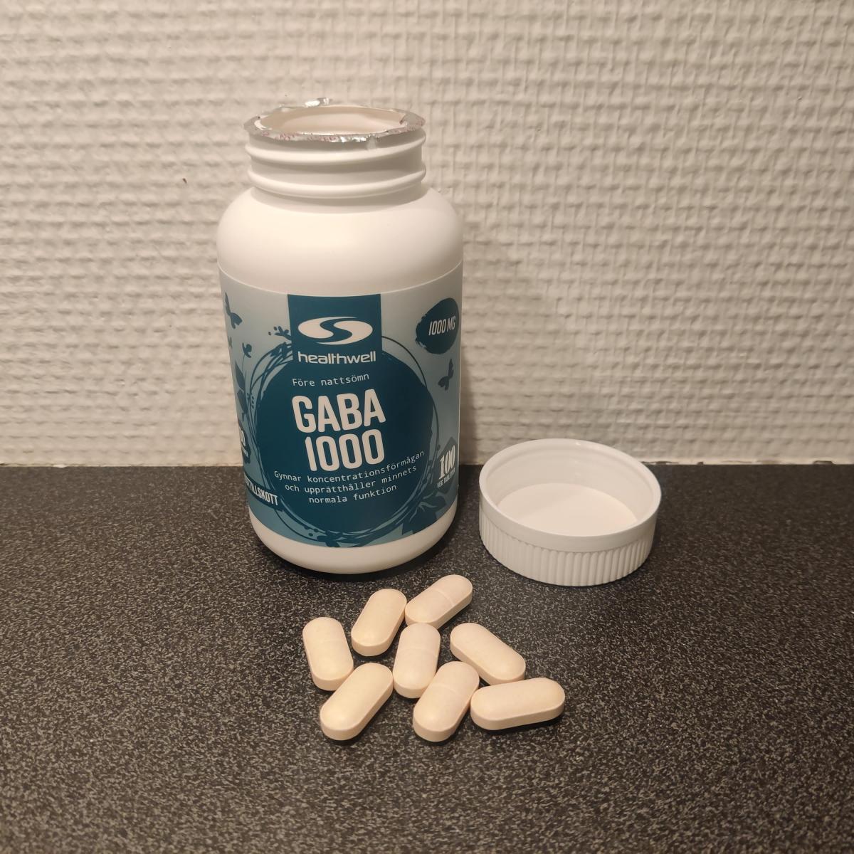 Öppen burk Healthwell GABA 1000 med tabletter framför, fotad av oss