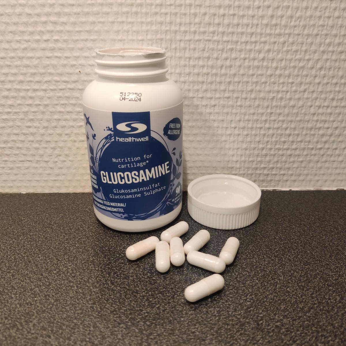 Healthwell Glukosamine med några kapslar bredvid burken fotograferad av oss