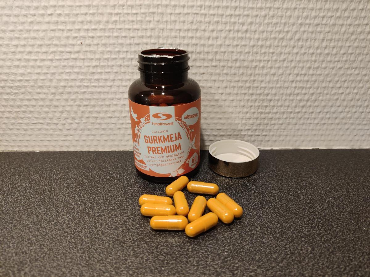 Öppen burk och utspridda kapslar av Healthwell Gurkmeja Premium på köksbänken