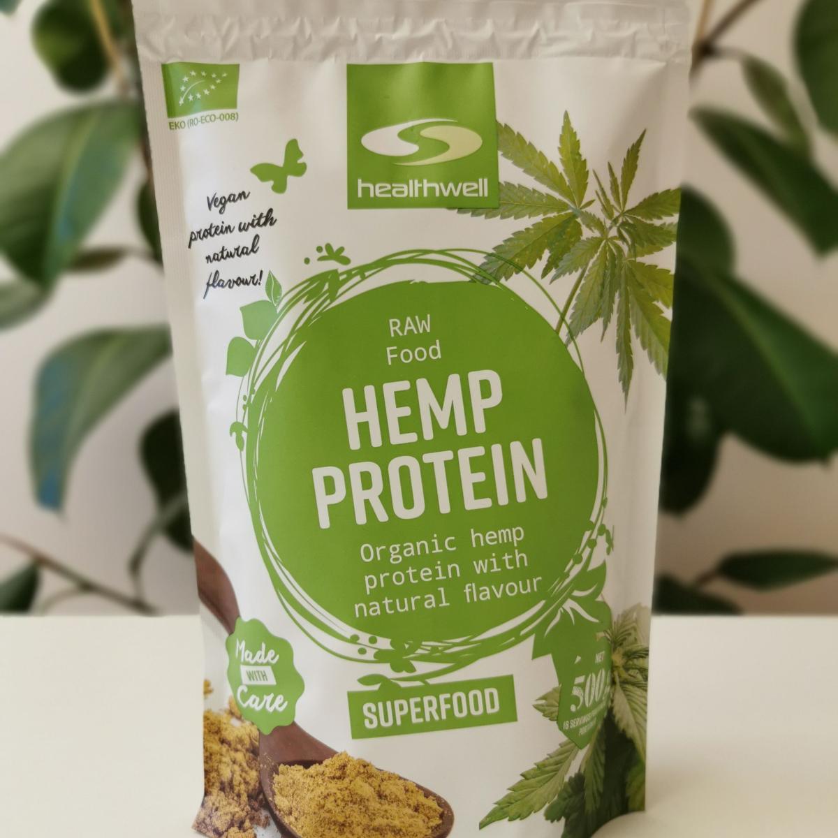 Healthwell Hampaprotein EKO på ljus bänk med grön växt i bakgrunden, fotad av oss
