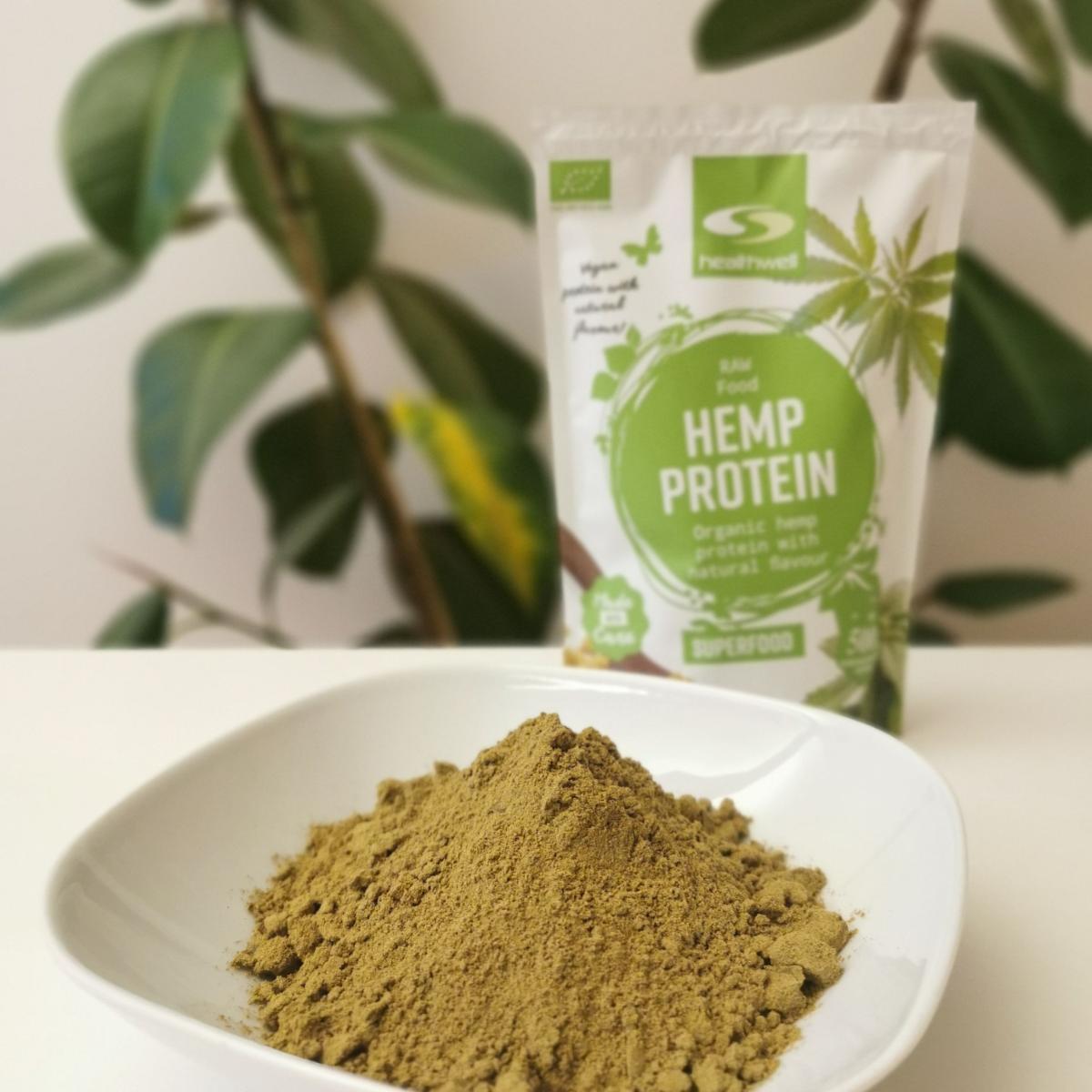 Hampaproteinpulver i vit skål med förpackningen suddad bakom, fotad av oss
