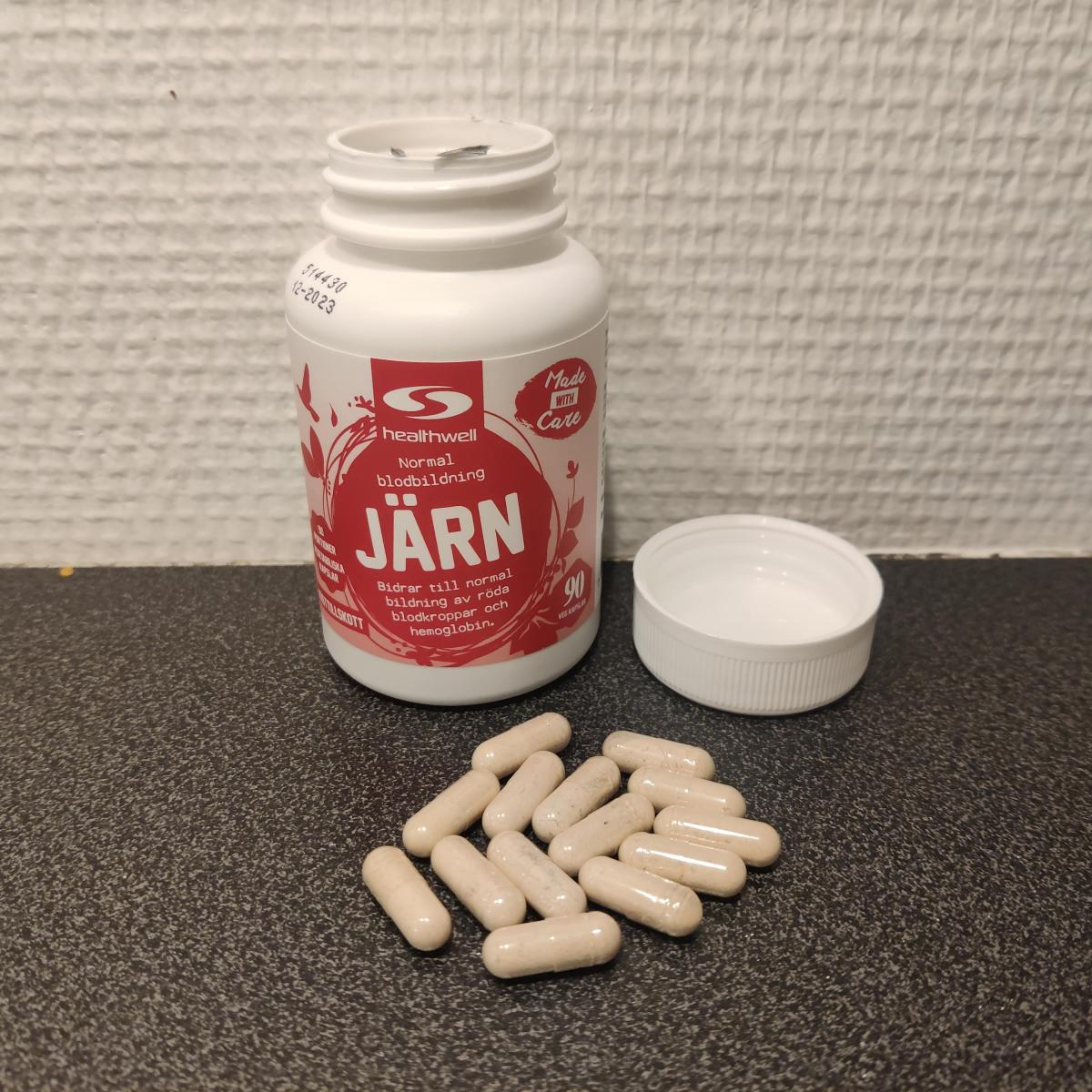 Healthwell Järn med kapslar intill burken på träyta, fotograferat av oss