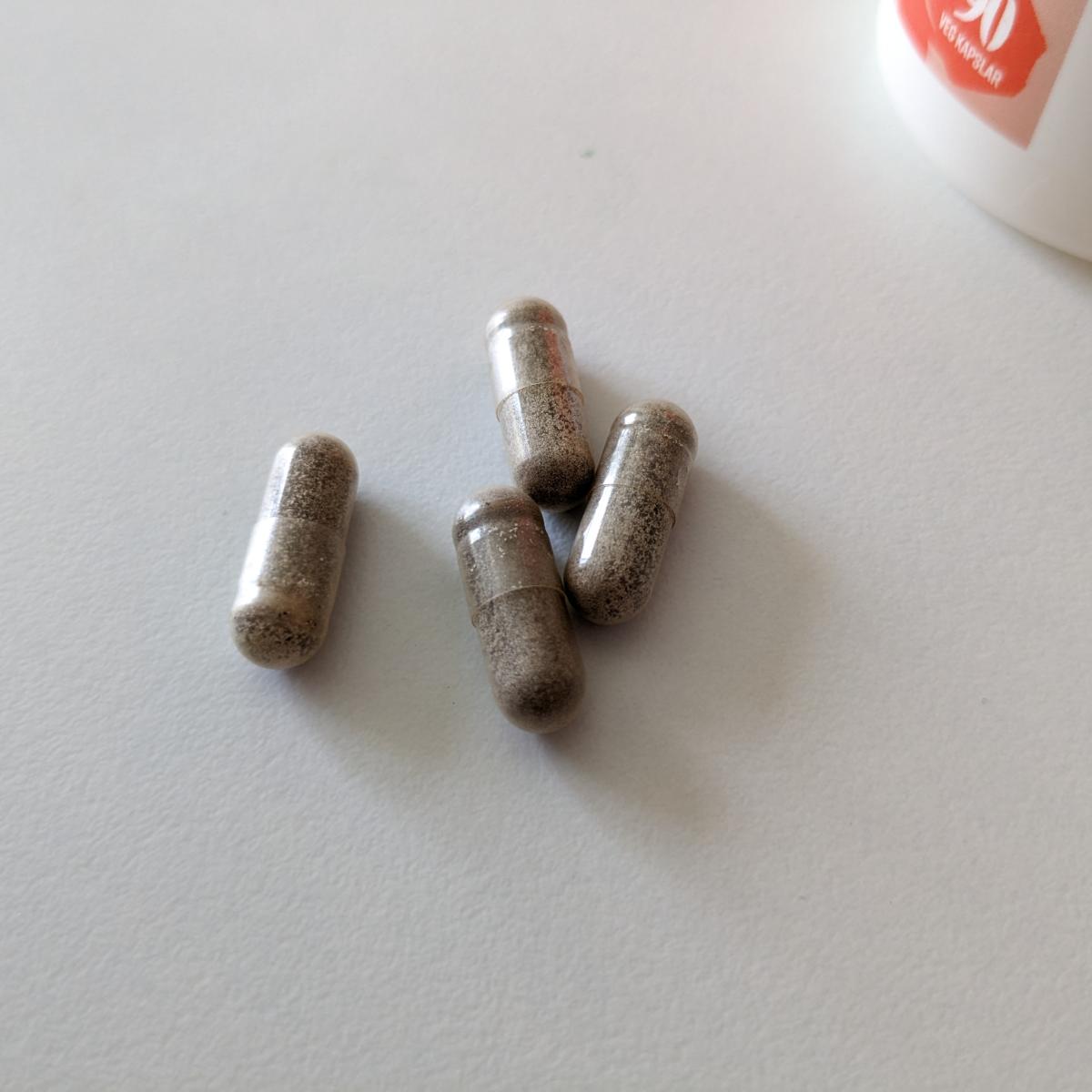 Kapsel från Healthwell Järn Skonsam bredvid linjal, ungefär 1,8 cm