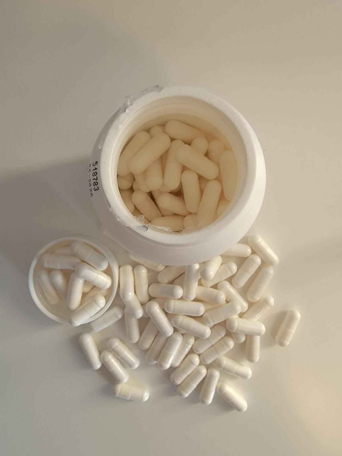 Vy uppifrån på öppnad burk med kapslar runtom, Healthwell Kalcium Magnesium, taget av oss