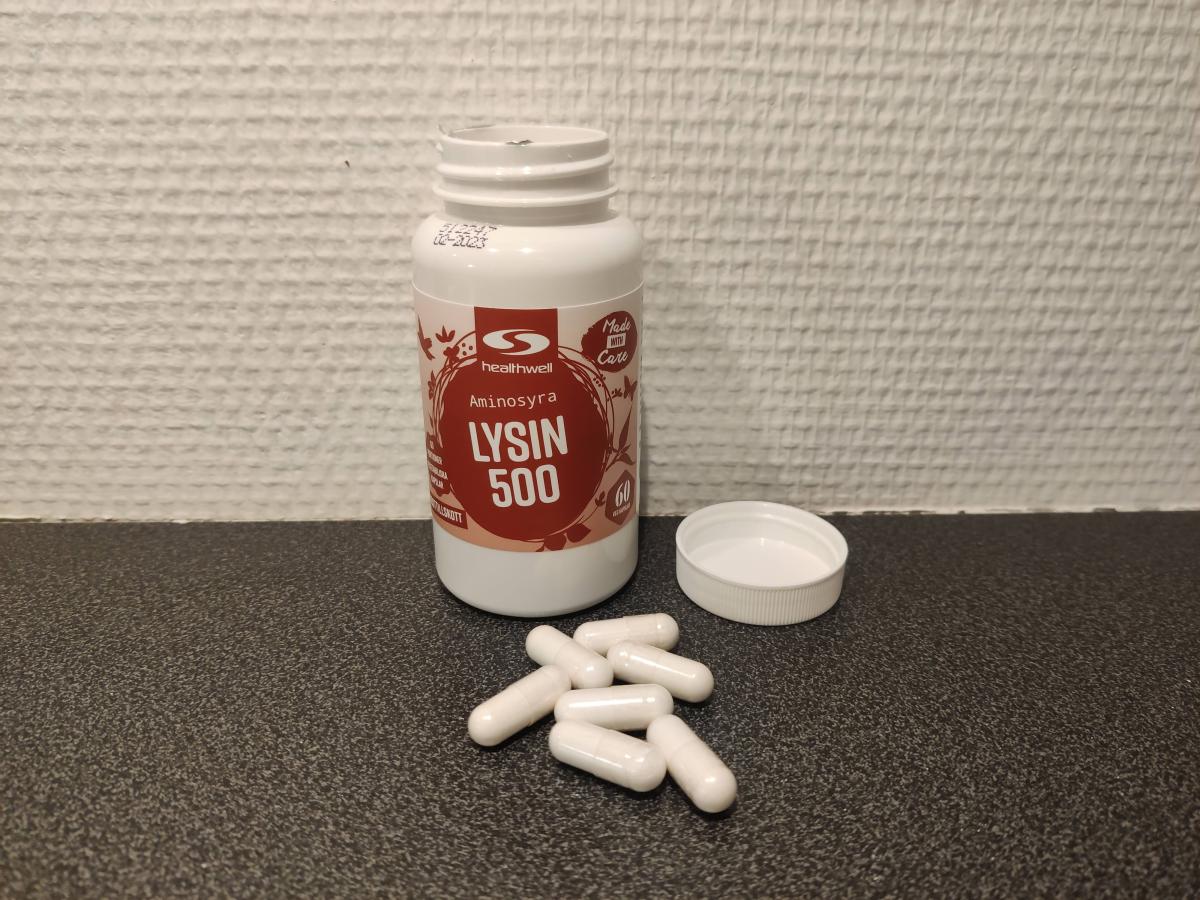 Öppnad burk Healthwell Lysin 500 med kapslar på bänken, egen testbild