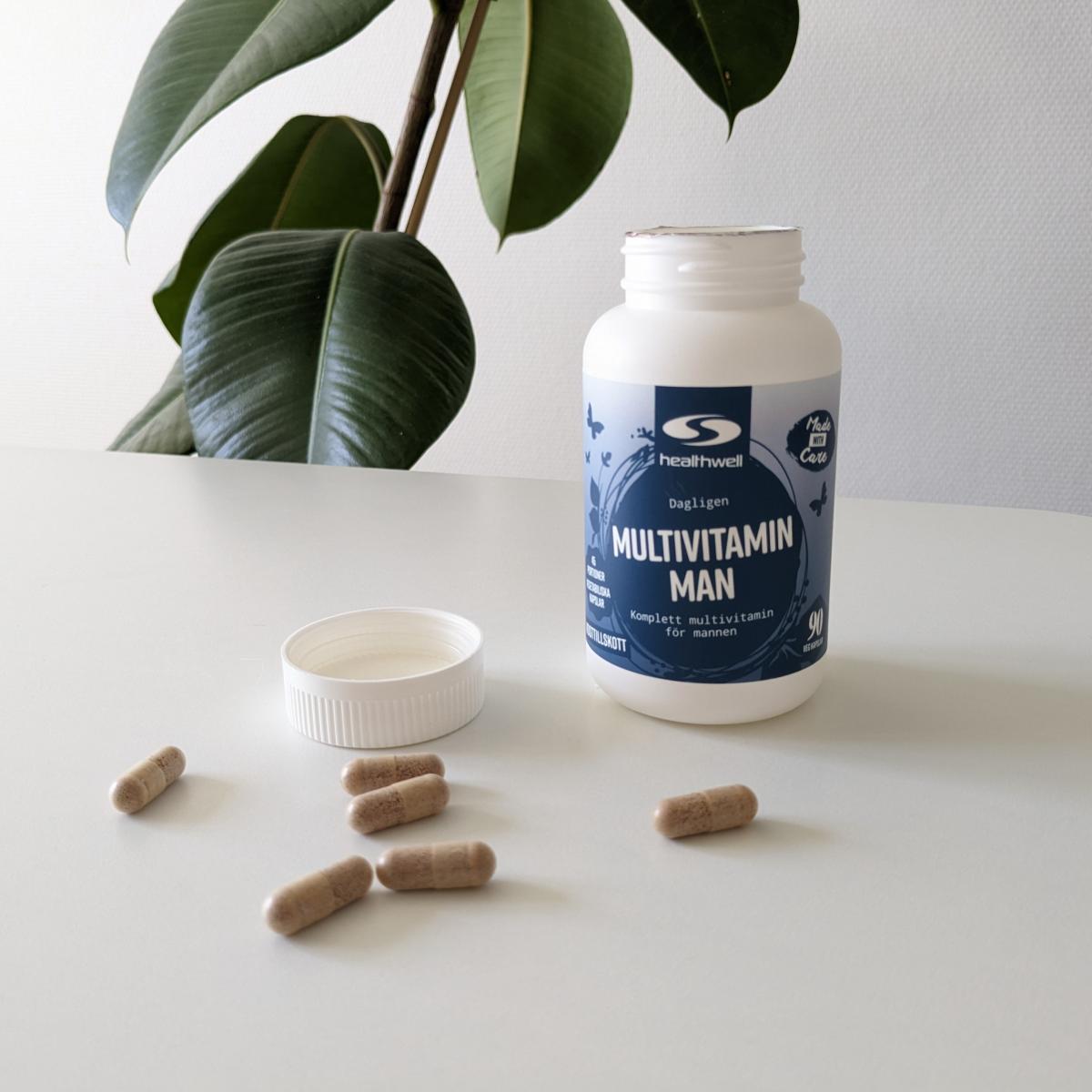 Healthwell Multivitamin Man fotograferad av oss under testet – öppen burk med kapslar på bord i naturligt ljus