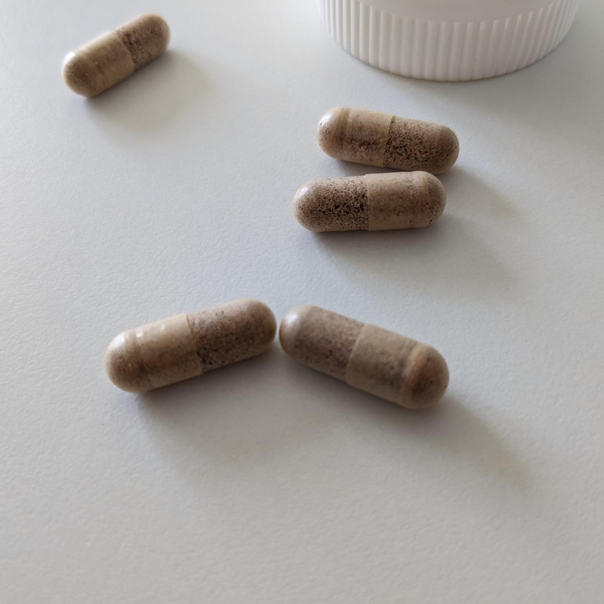 Närbild på Healthwell Multivitamin Man-kapslar tagna av oss; transparenta höljen som visar det finmalda innehållet