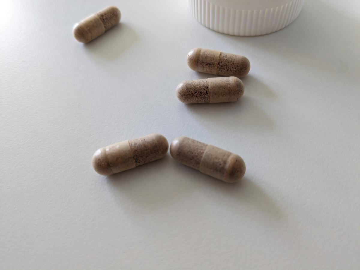 Närbild på Healthwell Multivitamin Man-kapslar tagna av oss; transparenta höljen som visar det finmalda innehållet