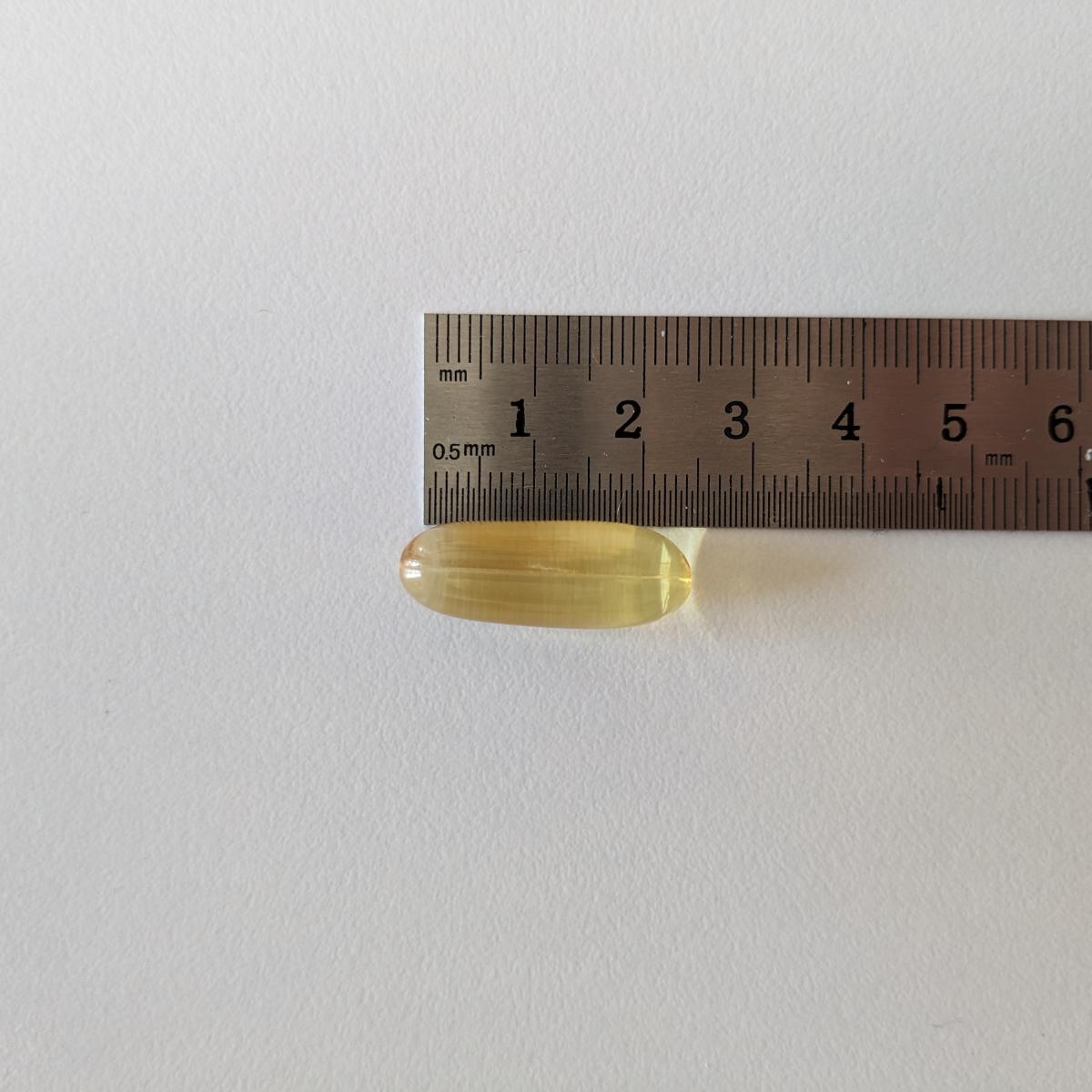 Kapsel från Healthwell Omega-3 Plus bredvid linjal cirka 23 mm, fotad under vårt test