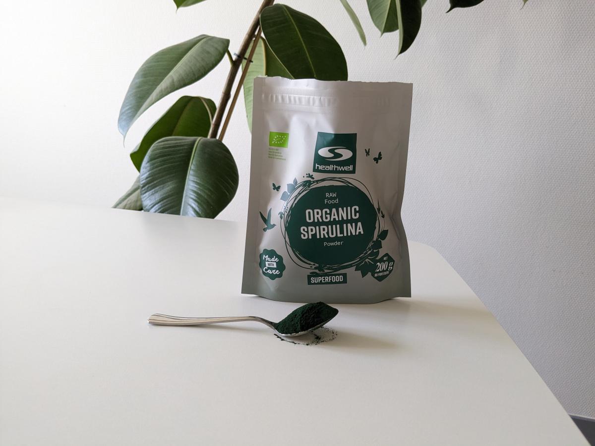 Healthwell Spirulina EKO på bord med sked pulver, egen testbild