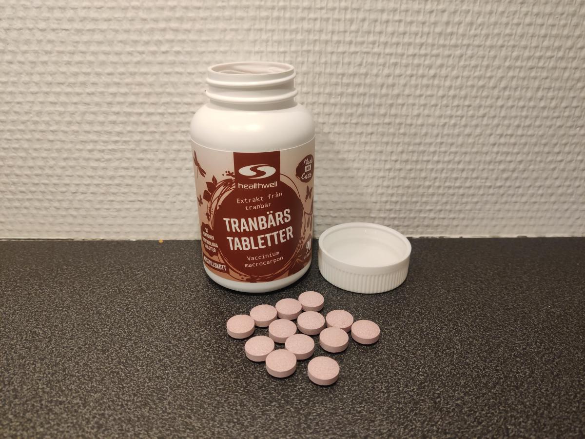 Öppen burk med rosa tranbärstabletter på bänkskiva, foto från vårt test