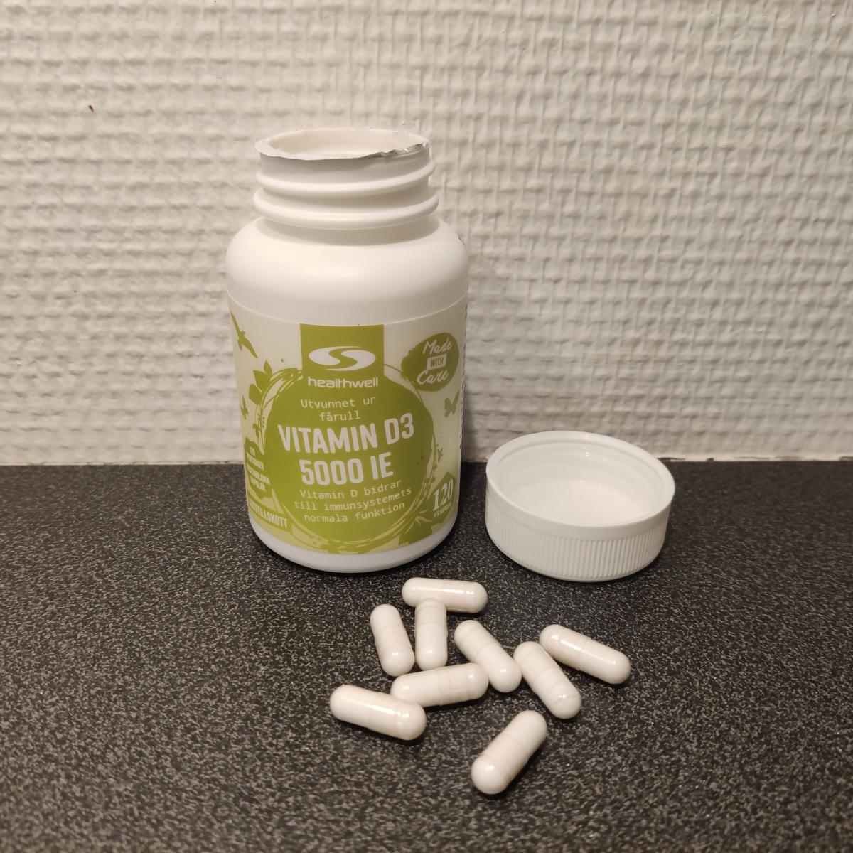 Healthwell Vitamin D3 5000 IE på träbord, vårt eget foto