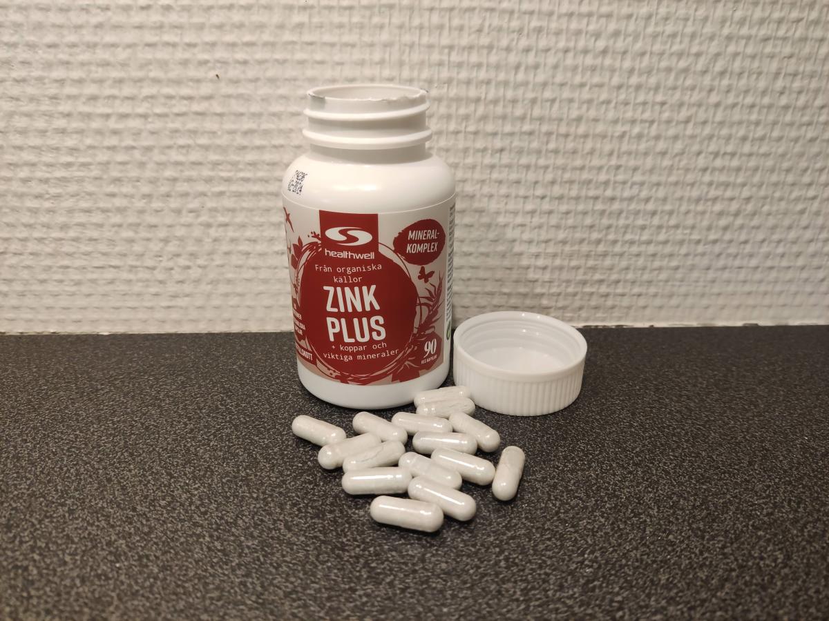 Healthwell Zink 25 Plus fotograferad av oss under testet, öppen burk med kapslar på mörk bänk