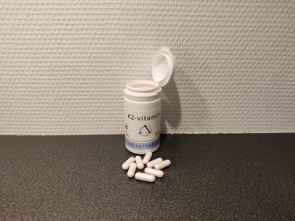 Helhetshälsa K2-Vitamin öppnad burk med kapslar på bänkskiva, fotad av oss under användning