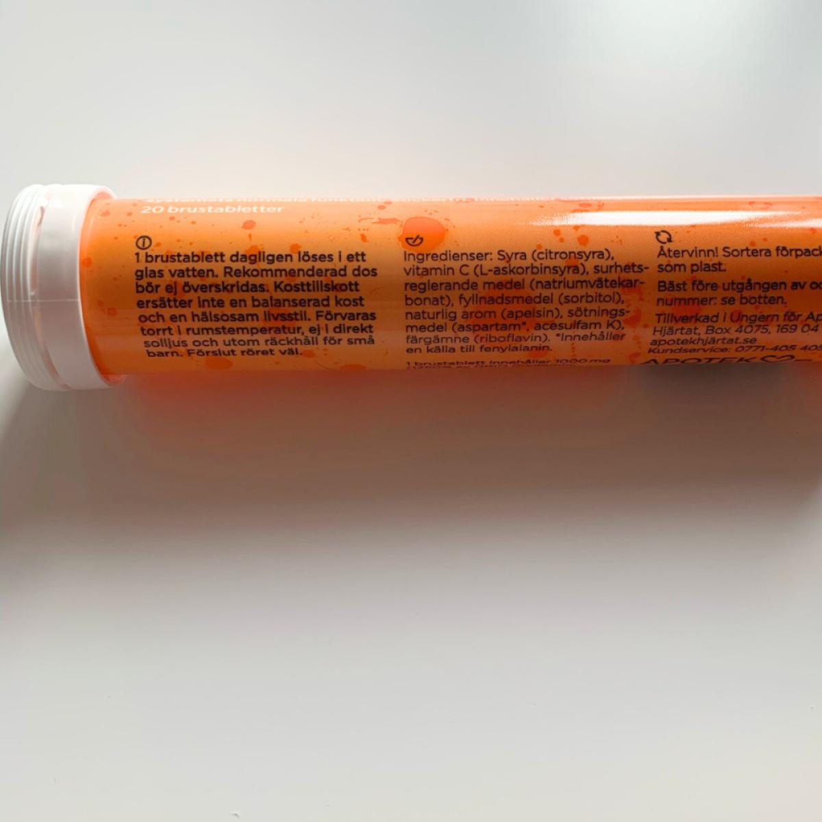 Pärlande glas C-vitamin i morgonljus med rör i bakgrunden, taget av oss