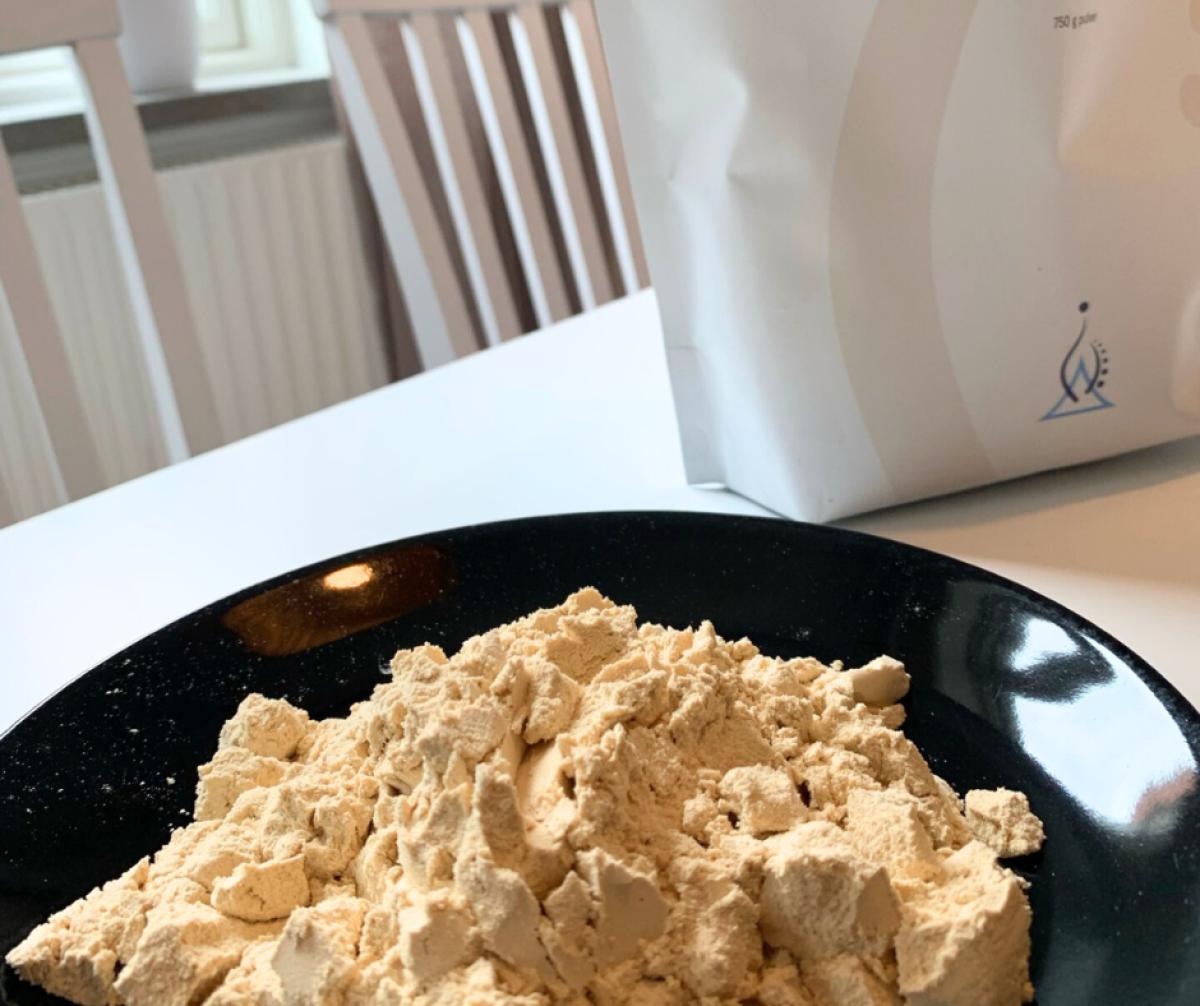 Ljust finmalet ärtprotein upplagt på tallrik med påsen i bakgrunden egen bild