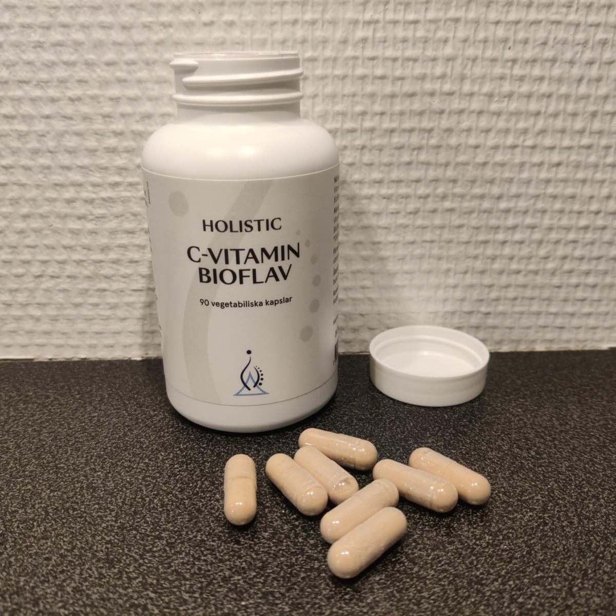 Närbild på Holistic C-Vitamin Bioflav med kapslar bredvid