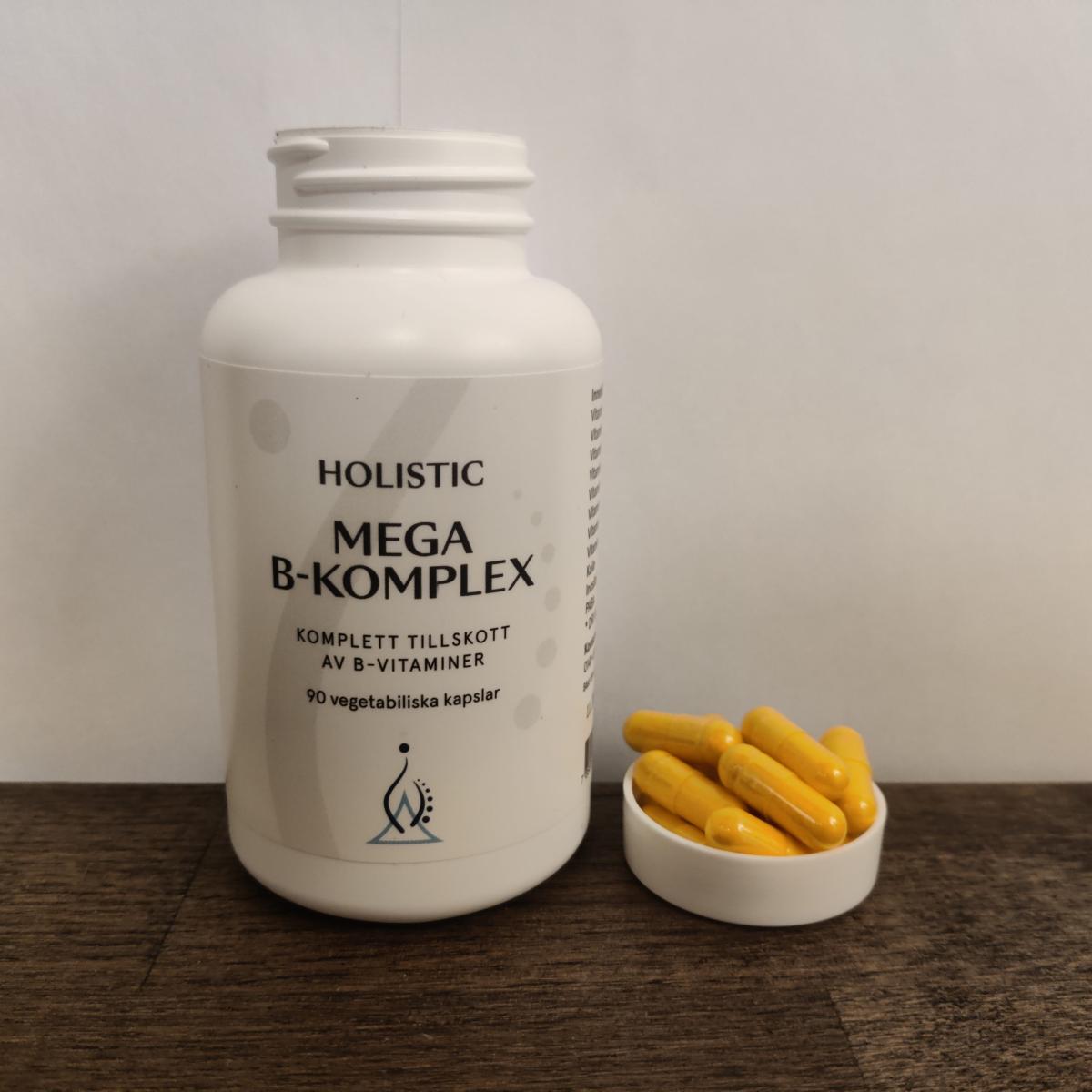 Holistic Mega B‑komplex på träbord med några kapslar bredvid – vårt foto