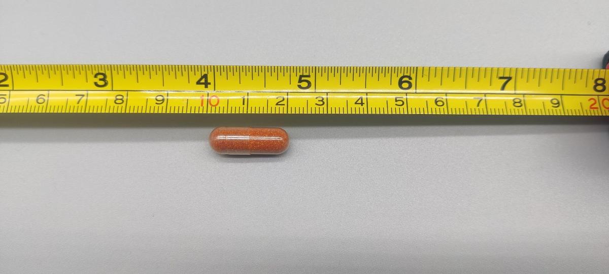 En Core Betakaroten-kapsel uppmätt mot måttband cirka 2 cm, vårt foto