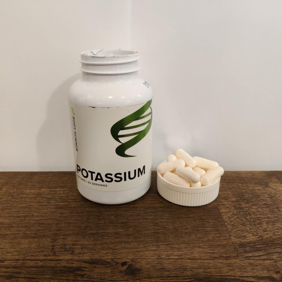 Kapslarna upplagda bredvid burken på träbord Body Science Kalium eget foto