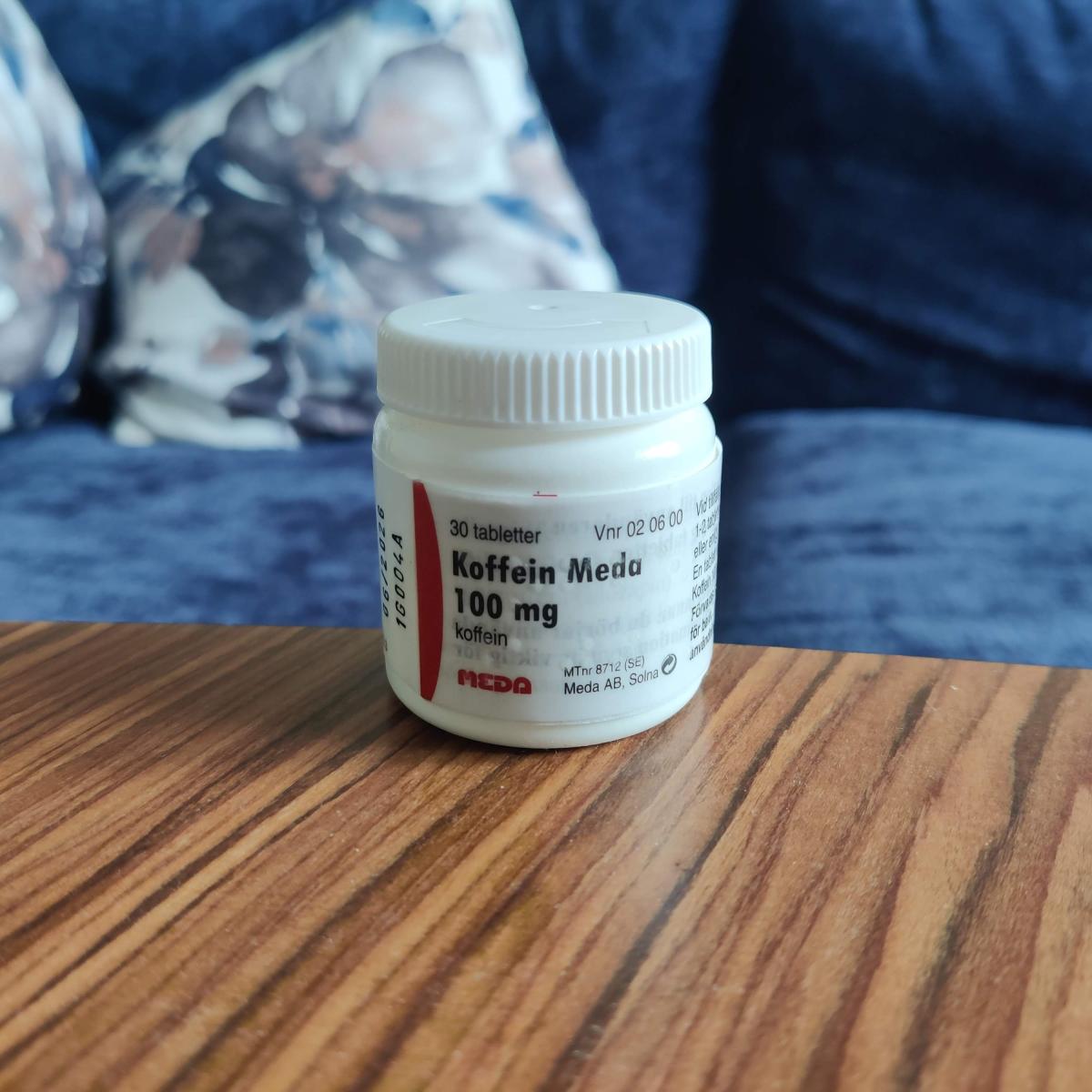 Meda Koffein 100 mg i liten vit burk på soffbordet, foto av oss