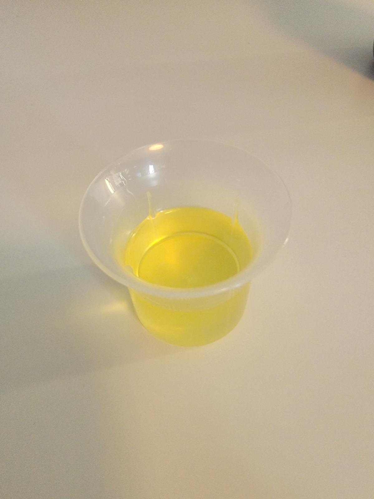 Närbild av den tunna, ljusgula oljan i provkopp tagen av oss