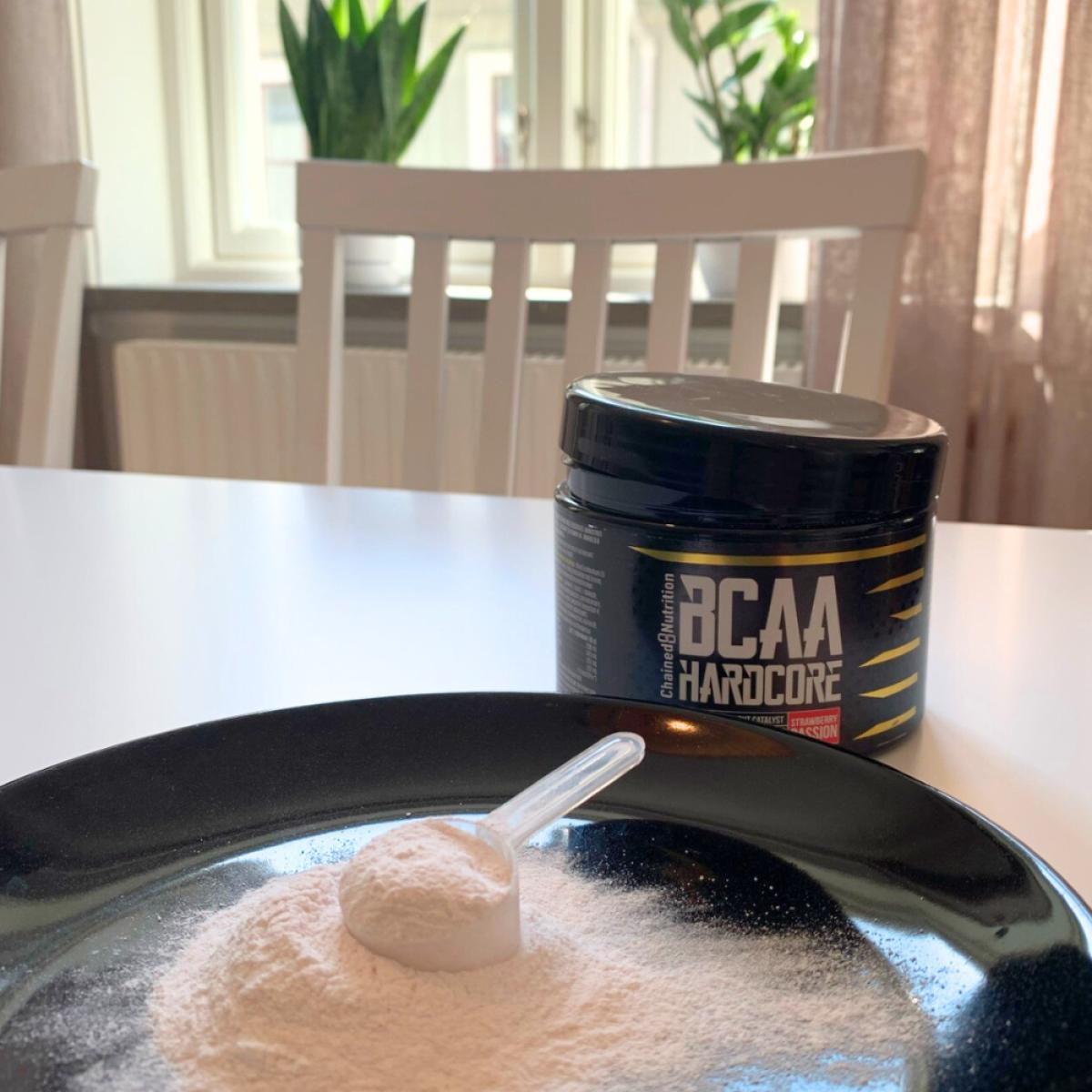 Närbild på skopa pulver i dagsljus med BCAA-burk i bakgrunden, vår testbild