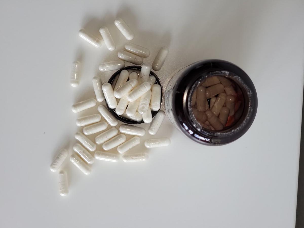 Top-down vy av Närokällan D3 5000 Vegan med spridda kapslar och öppen flaska, fotograferad av oss