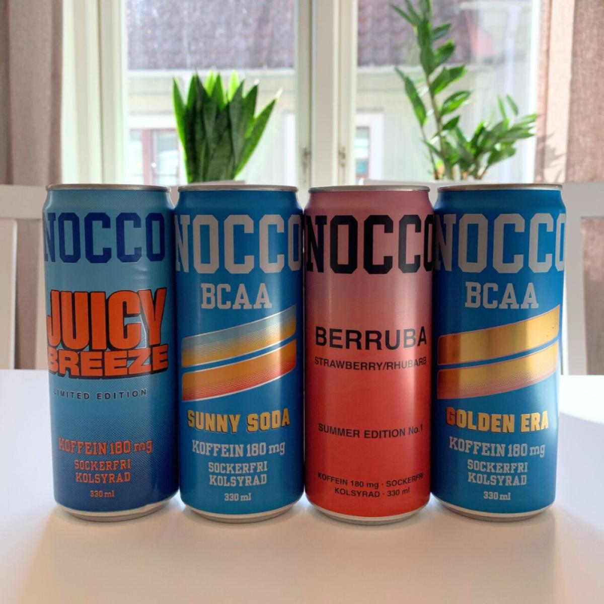 Fyra NOCCO BCAA-burkar i fönsterljus under vårt test Juicy Breeze Sunny Soda Berruba och Golden Era fotade av oss