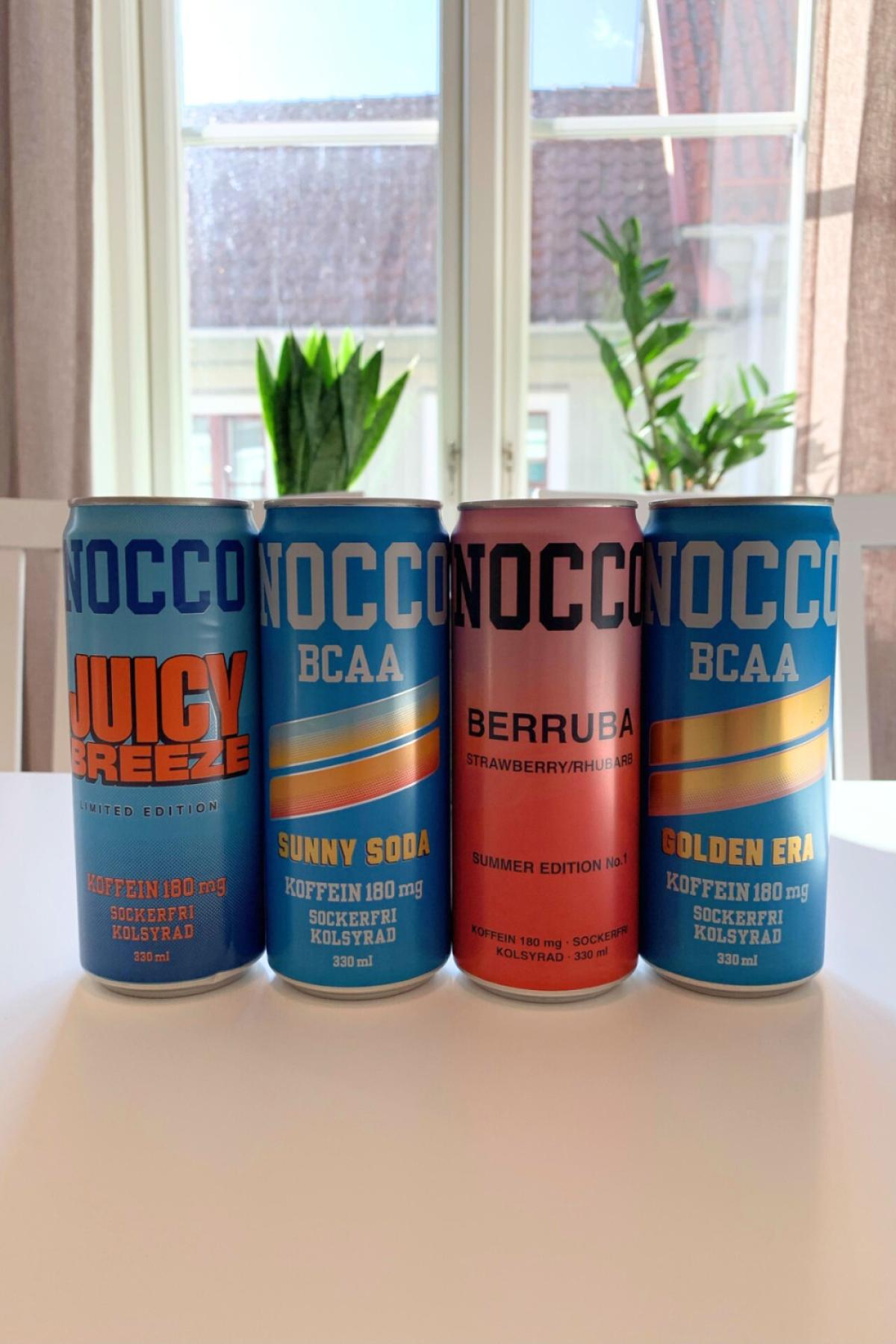 Fyra NOCCO BCAA-burkar i fönsterljus under vårt test Juicy Breeze Sunny Soda Berruba och Golden Era fotade av oss