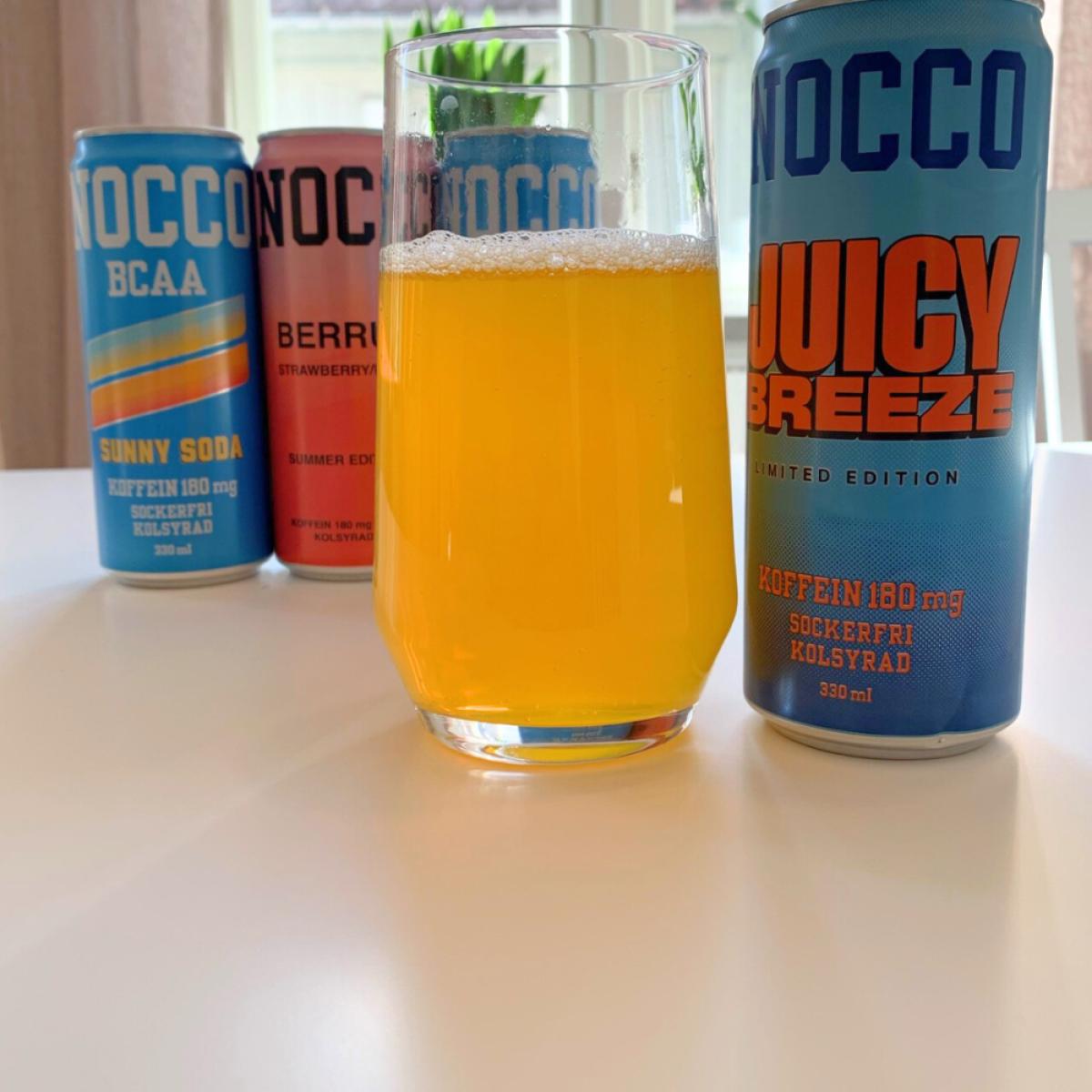 Juicy Breeze upphälld i glas framför övriga NOCCO-burkar från vårt test