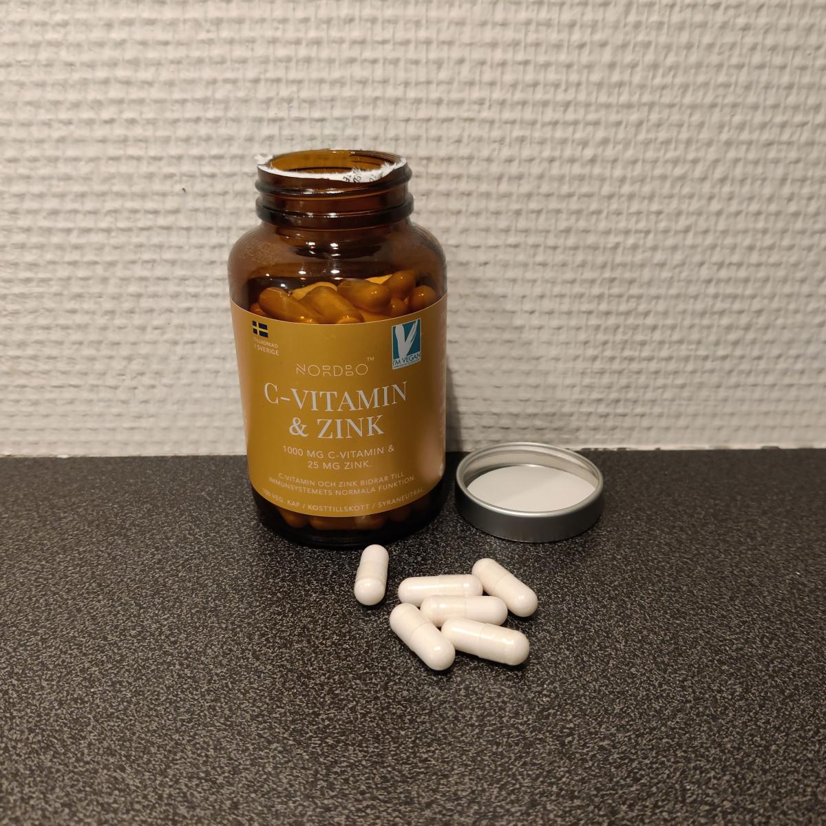 Nordbo C‑vitamin & Zink på träbord i dagsljus med kapslar bredvid, taget av oss under testet