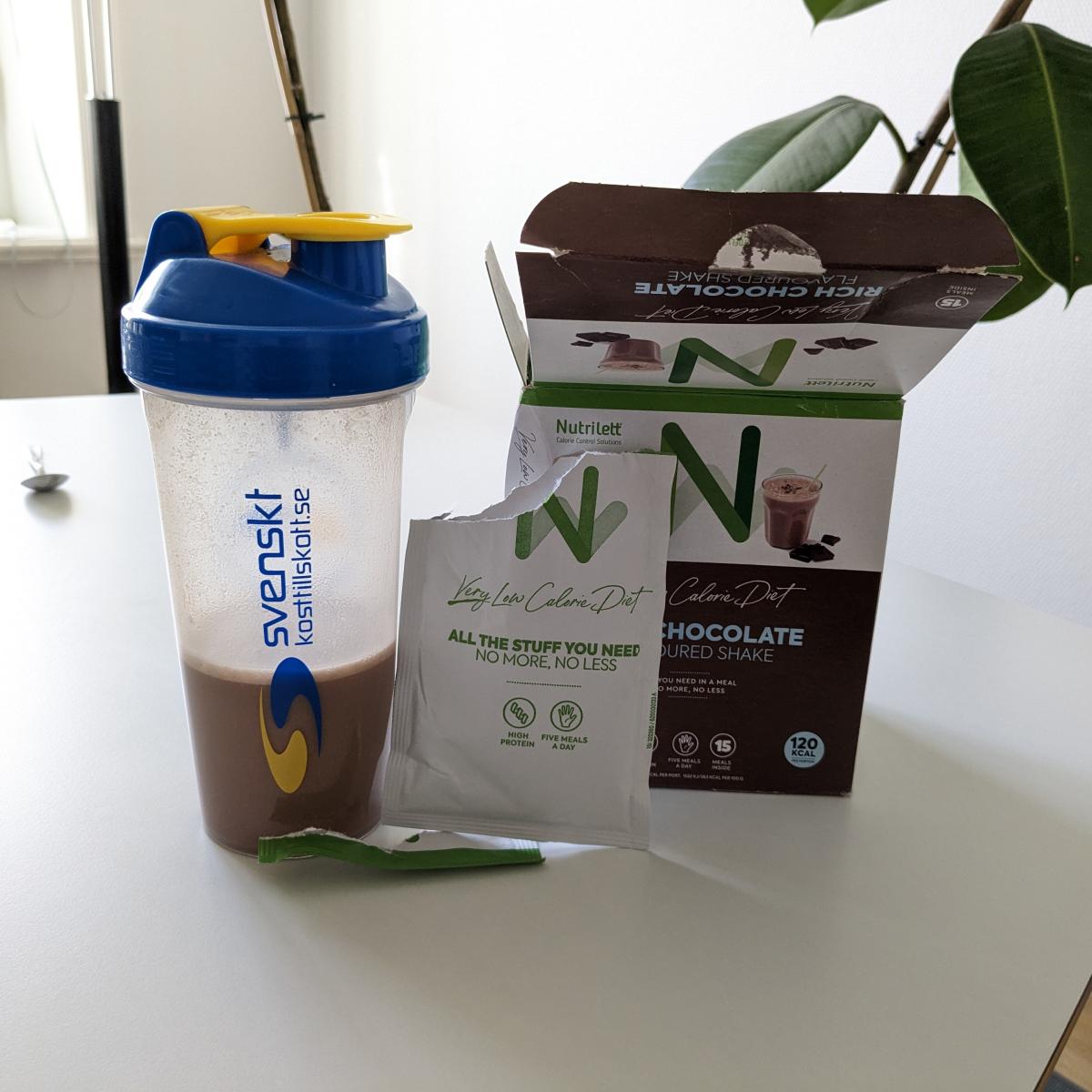 Färdigblandad Nutrilett chokladshake i shaker bredvid öppnad kartong tagen av oss