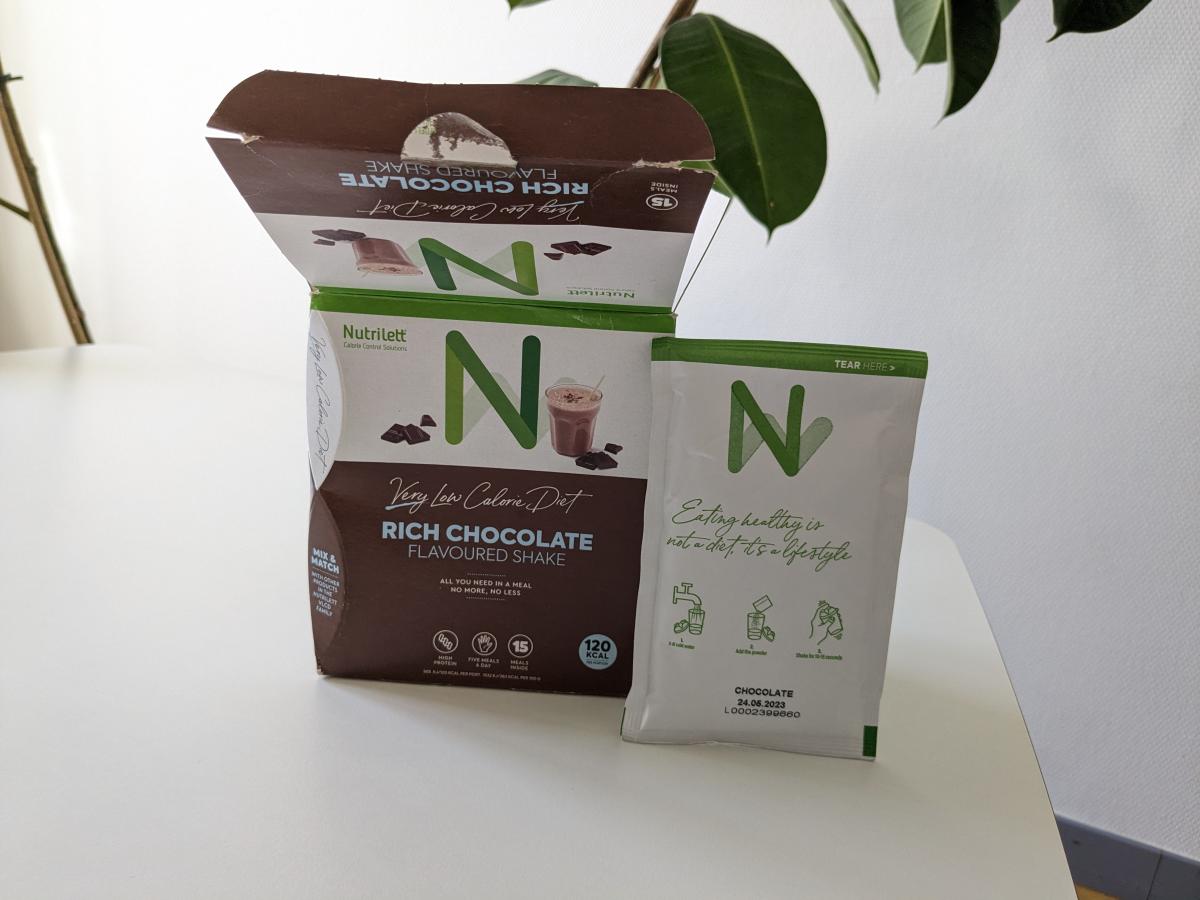 Nutrilett Rich Chocolate kartong med fristående portionspåse på bord tagen av oss