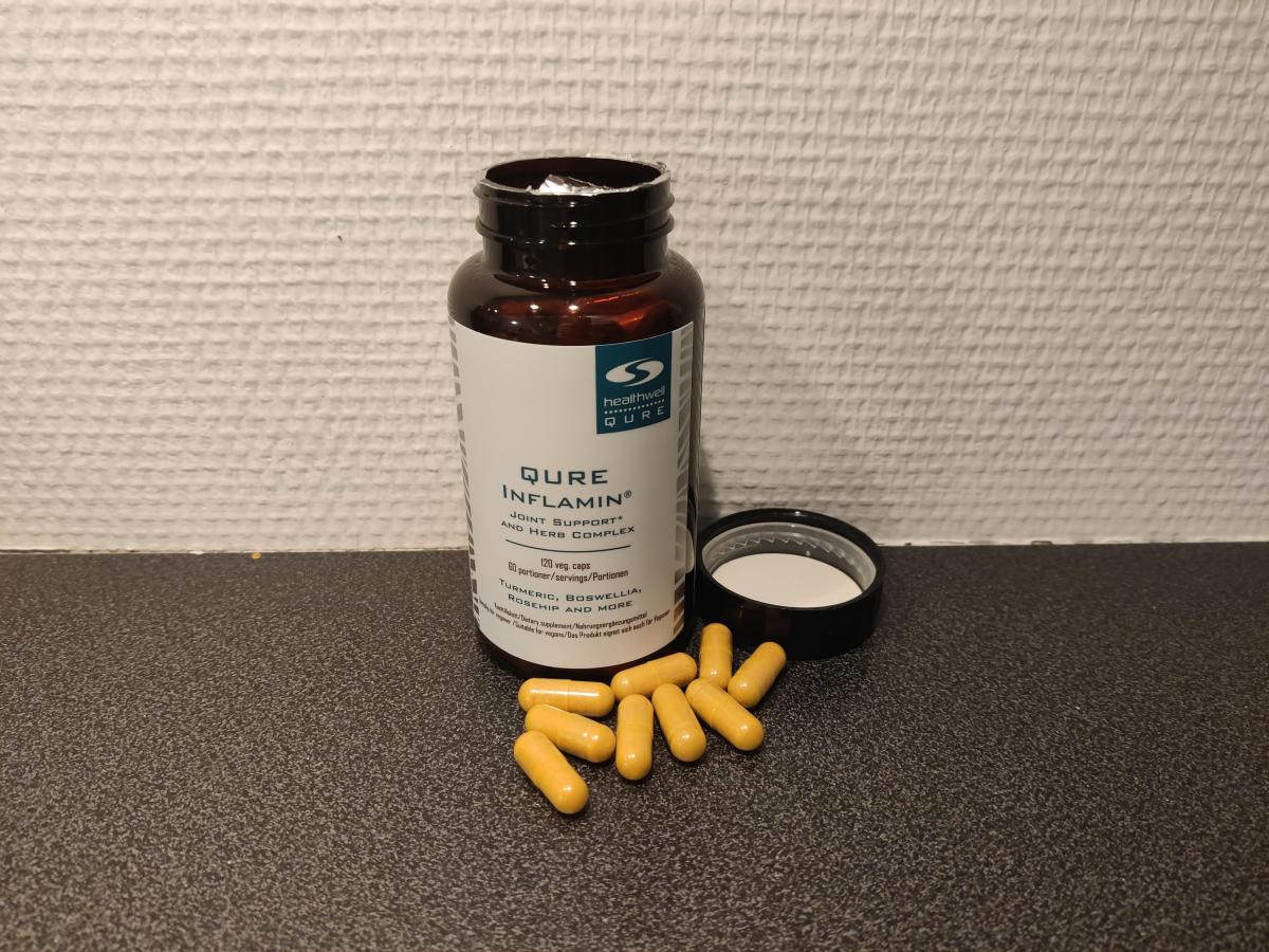 Öppen burk med Inflamin Premium och kapslar på köksbänken, fotad av oss