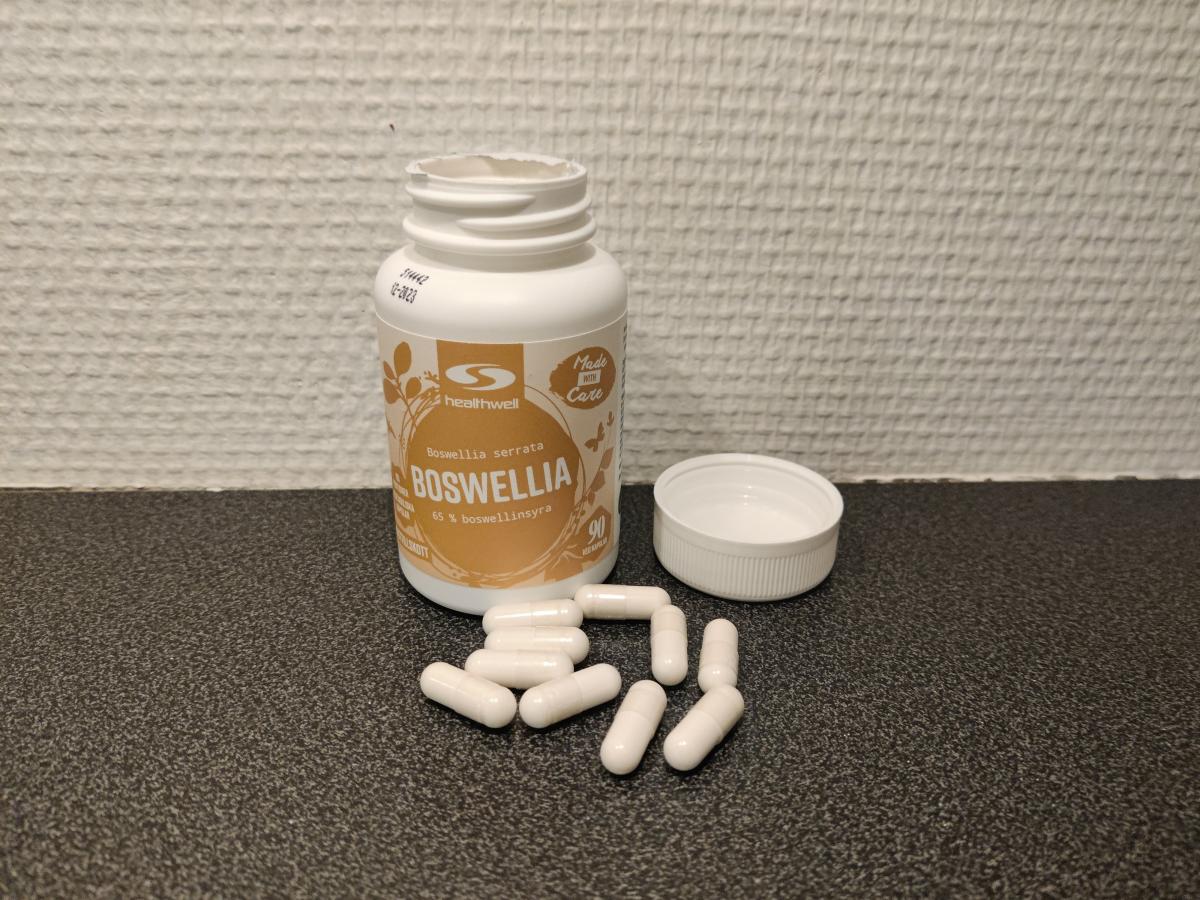 Öppnad burk och utspridda kapslar av Healthwell Boswellia i köksljus, foto taget av oss