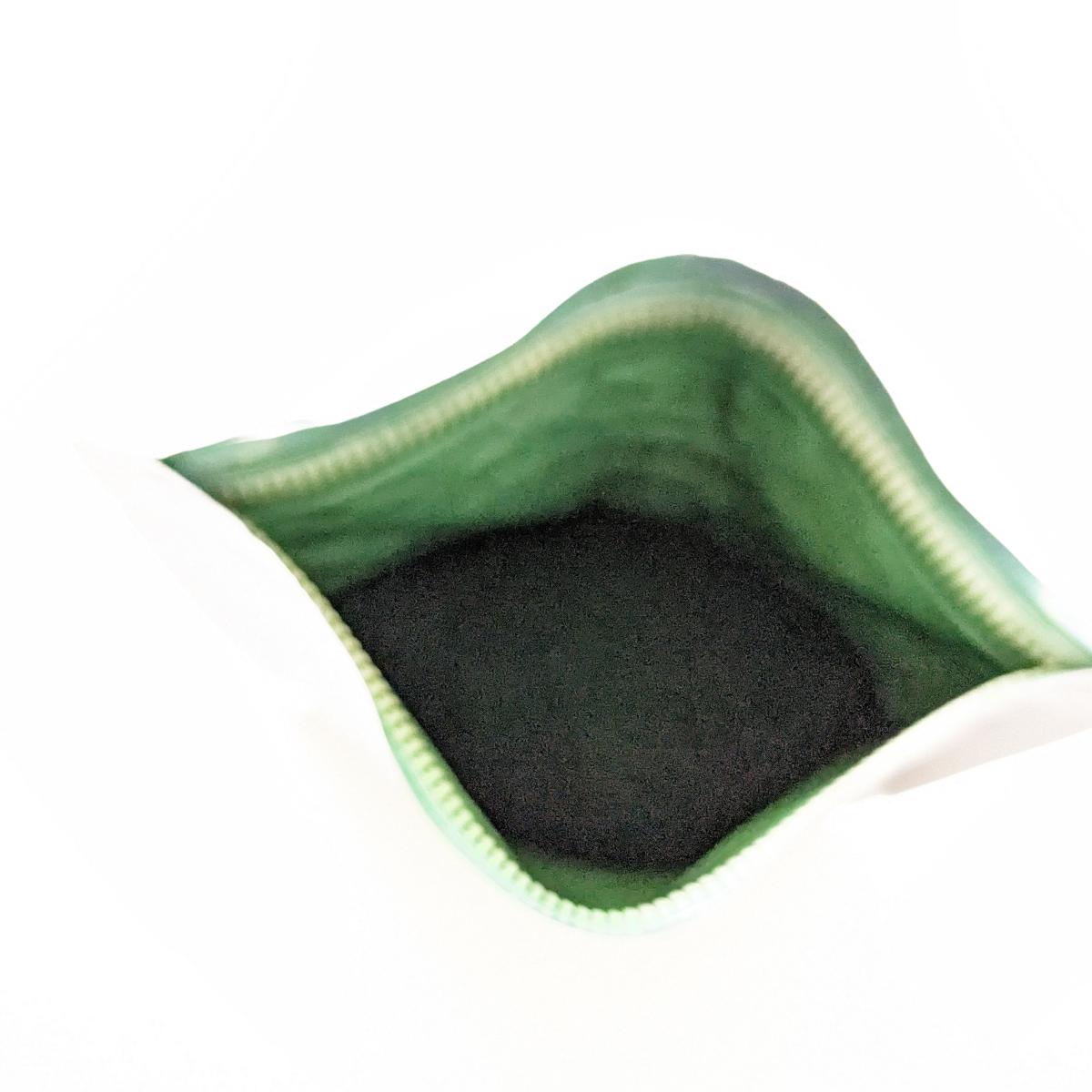 Healthwell Spirulina EKO på bord med sked pulver, egen testbild