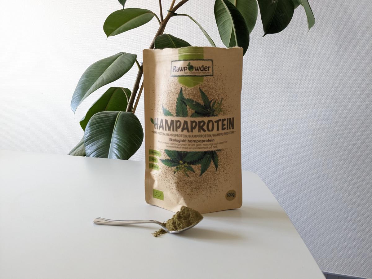 Rawpowder Hampaprotein EKO och en sked pulver på bordet, fotograferat av oss