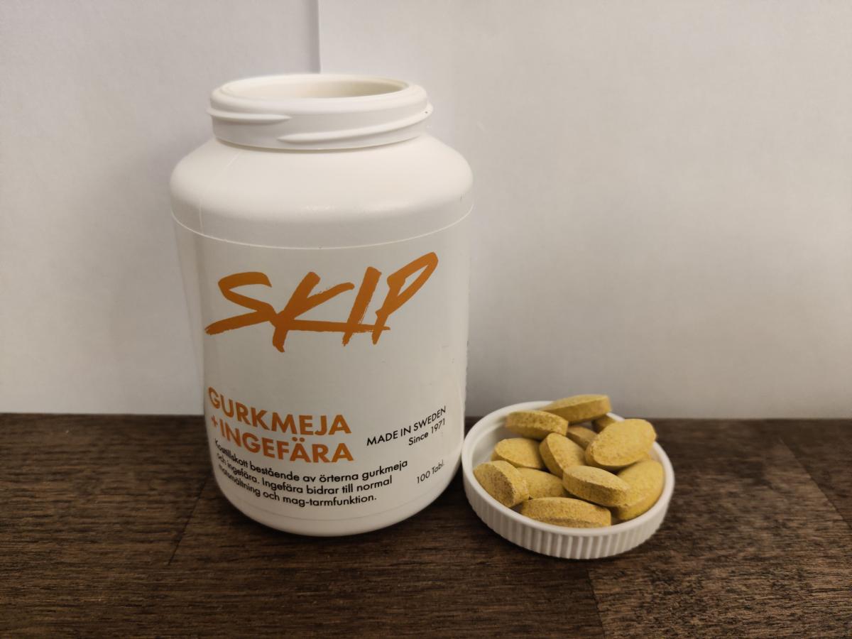 Burk och flera tabletter samlade intill på träyta, nära produktens front