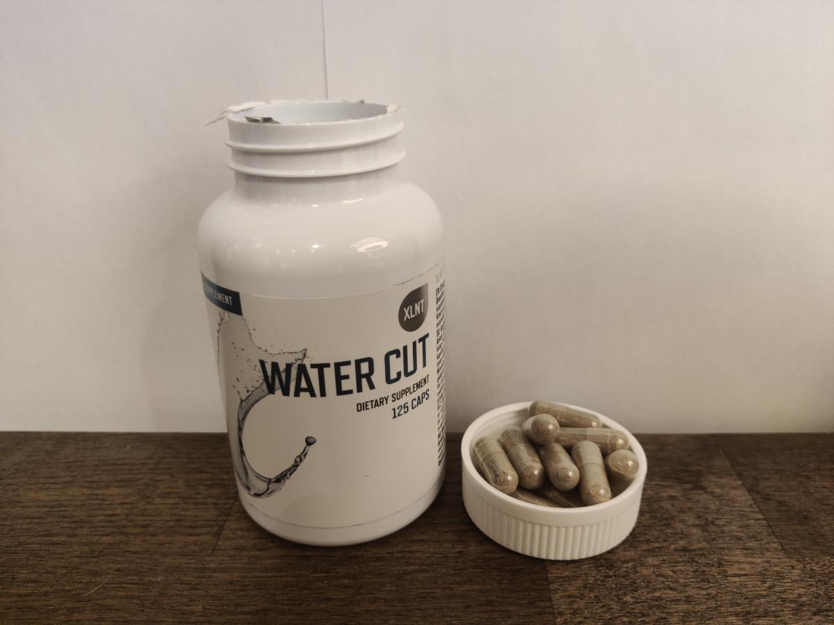 Water Cut med några kapslar i locket på träbord, taget av oss