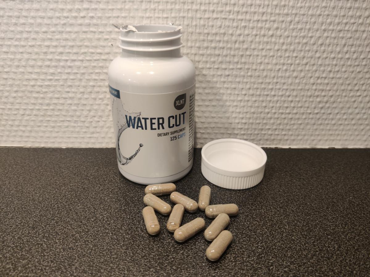 XLNT Sports Water Cut öppnad med kapslar på bänken, foto taget av oss under testet